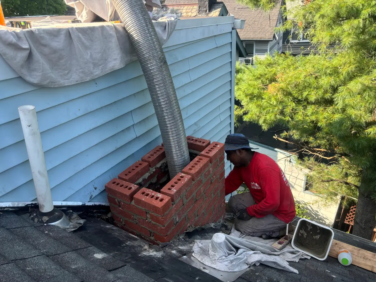 An A1 Action crew member laying brick on a new chimney base on a roof