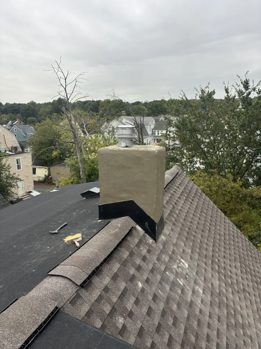 A chimney finished in fresh parge coat with new flashing where it meets the shingles