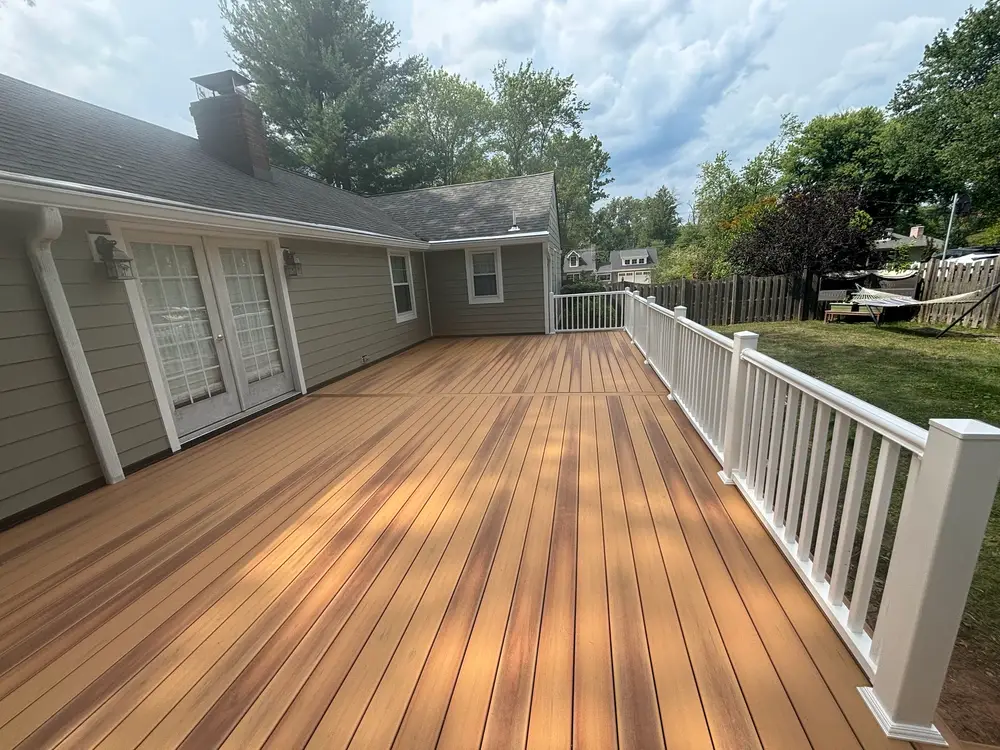 A composite deck laid in warm brown boards, enclosed by a white railing