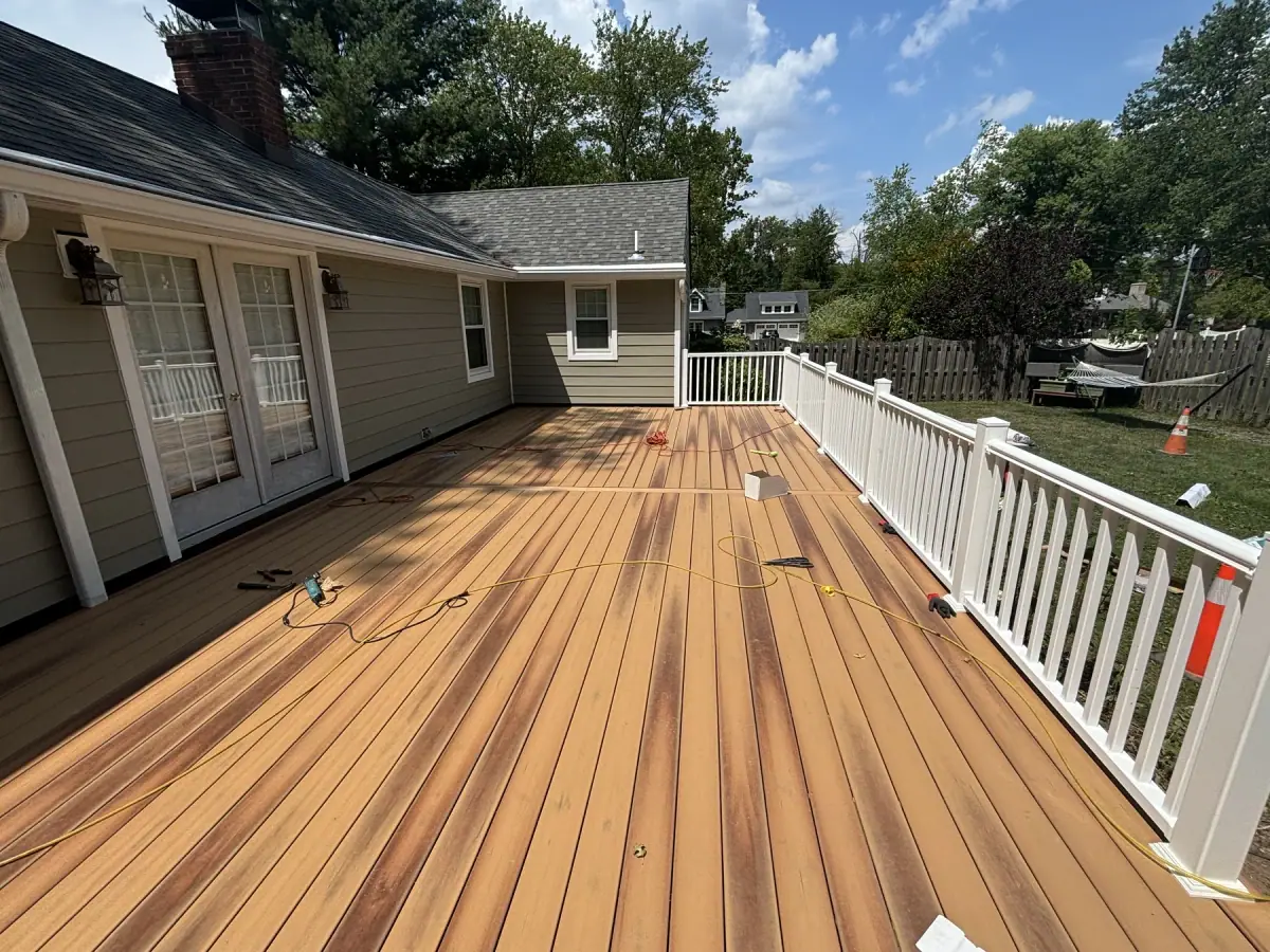 A finished composite deck in warm brown boards with a white railing along the edge