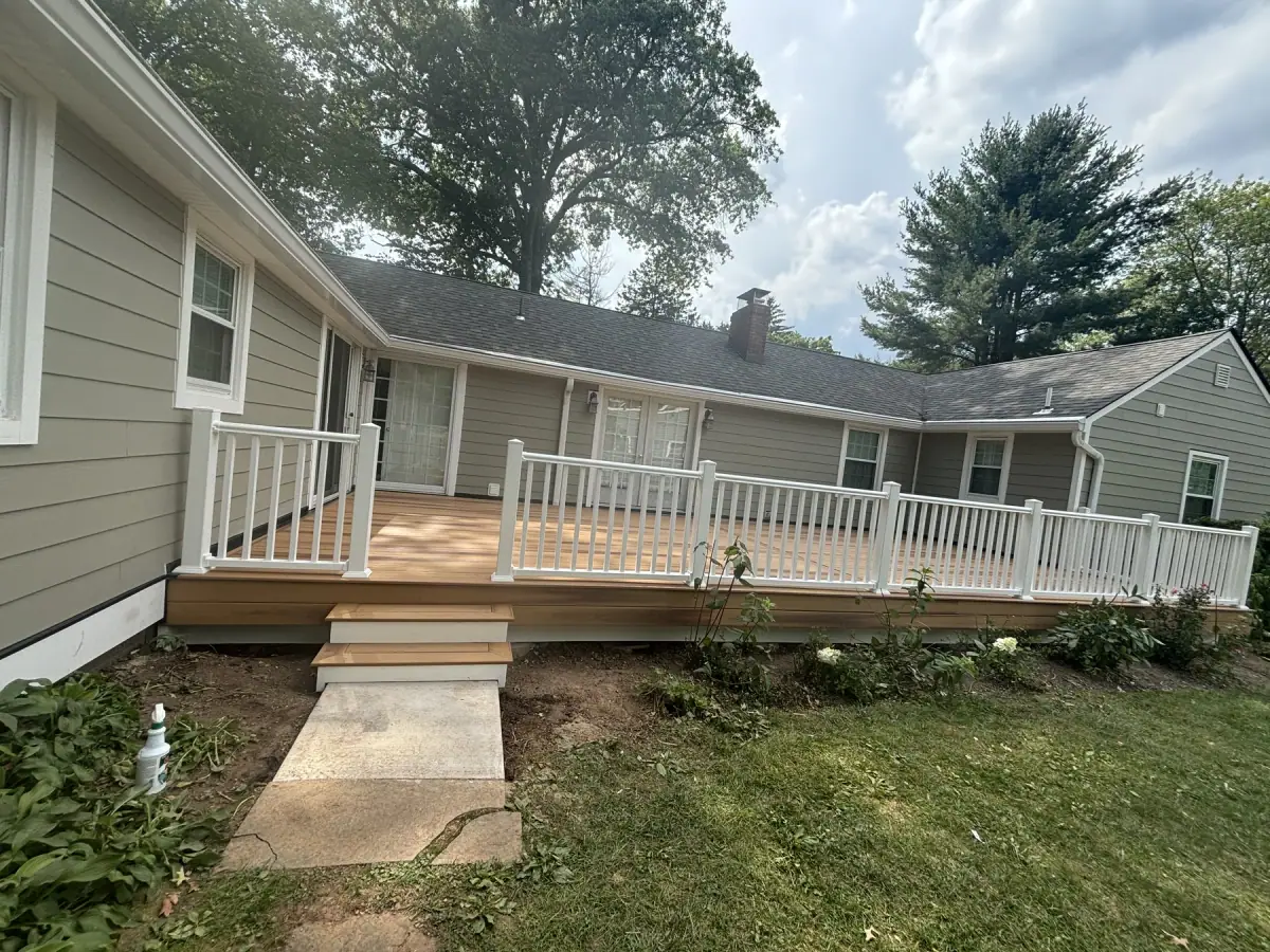 A finished deck with white railings and steps down to the lawn, seen from the garden