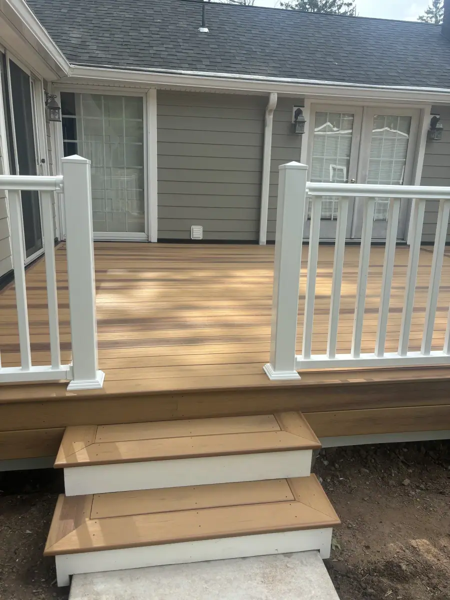 Deck steps and a white railing at the back door of a house