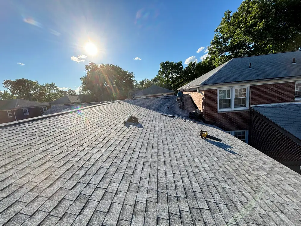 A newly shingled roof with the morning sun low and bright above the ridge