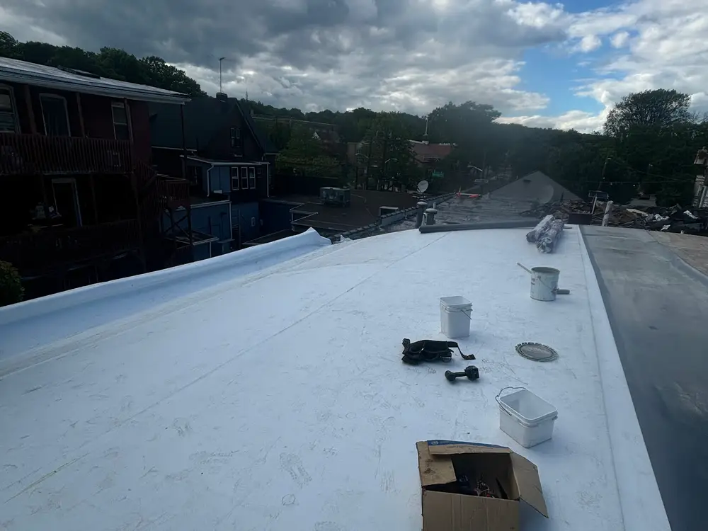 A finished white membrane flat roof with materials still set out at the edge