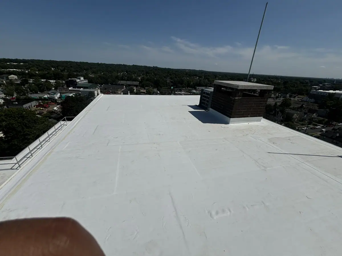 A finished white flat roof with a chimney, looking out over a wooded valley