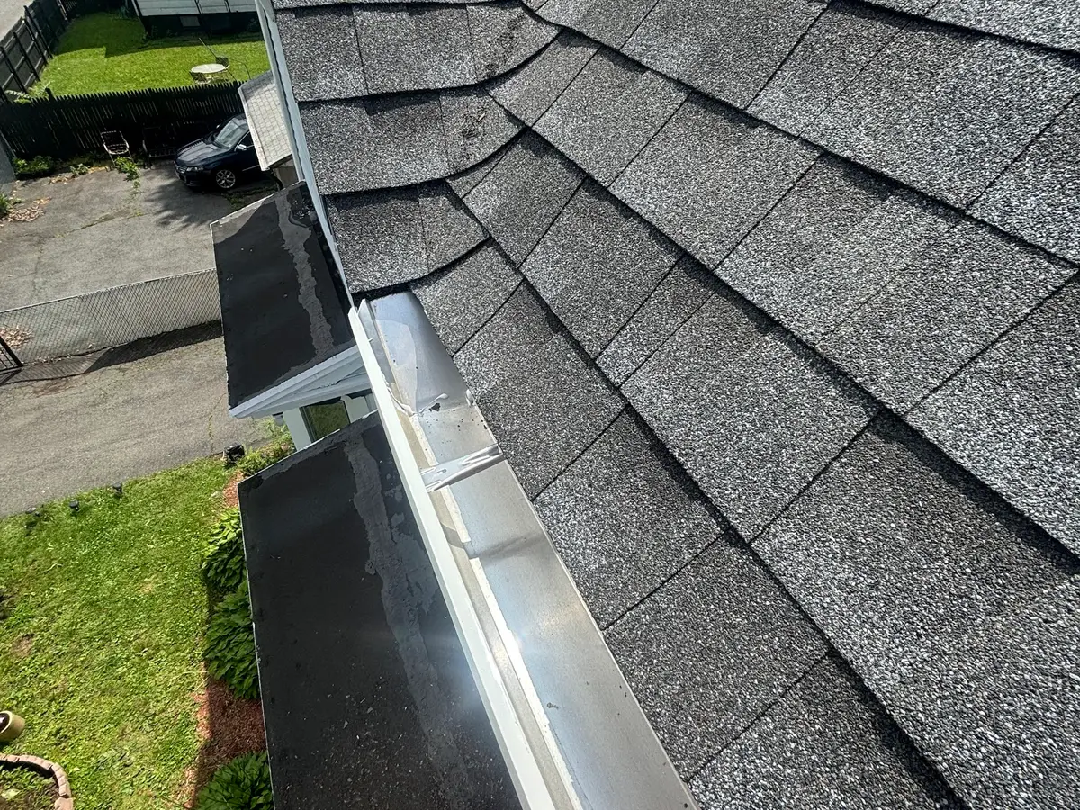 A new aluminium gutter running along the edge of a shingle roof