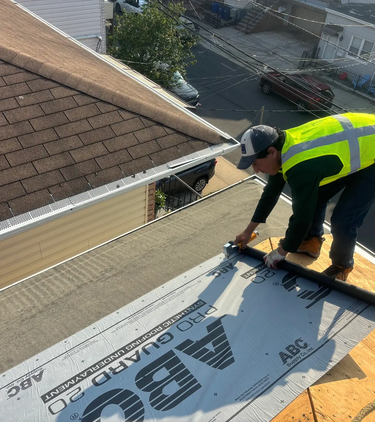 A roofer fitting new drip edge along the eaves over fresh underlayment