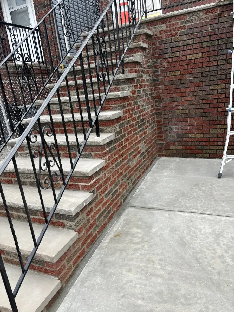 Finished brick steps with an iron railing and a new concrete apron at the bottom