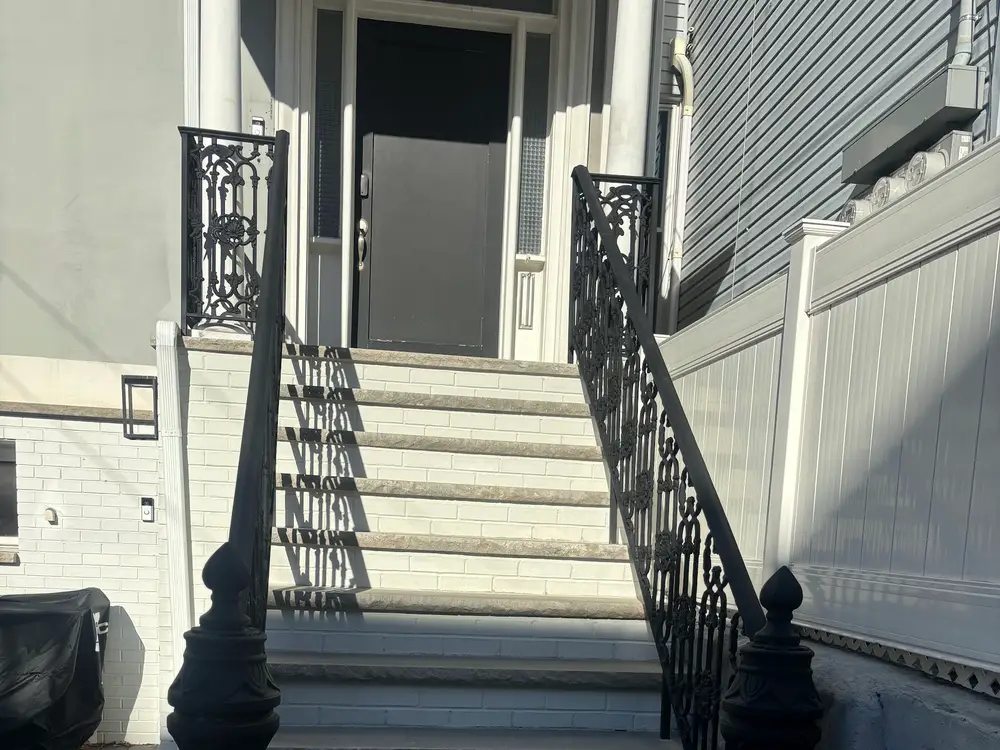 New entry steps finished with ornate black iron railings on both sides