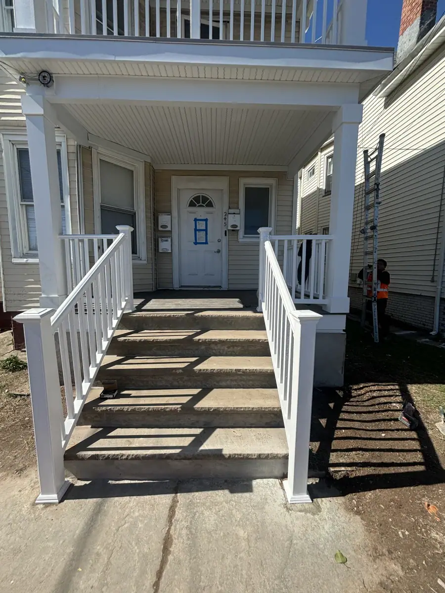 A finished porch with white railings and new treads leading up to the front door