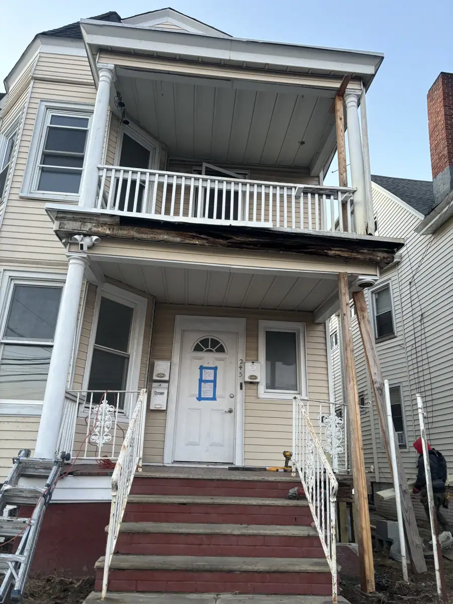 A two family porch with the roof edge sagging and the trim boards failing