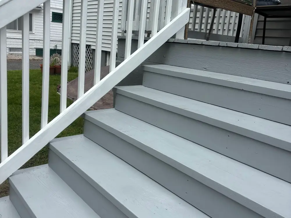 New porch steps finished in grey treads with a white rail alongside