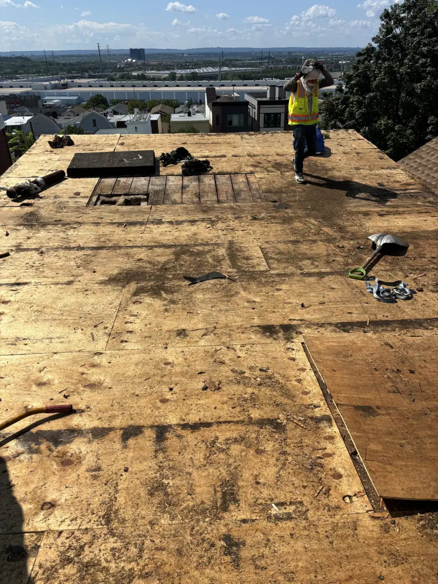 A large roof stripped to its original plank decking, a crew member crossing it