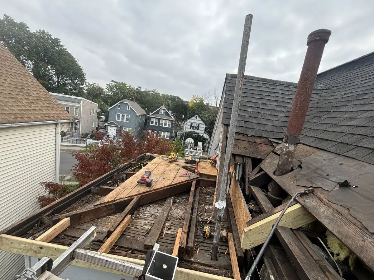 Old roof boards and debris lifted away, the framing beneath opened up