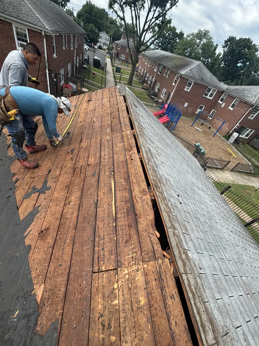 Bare wooden plank decking exposed after a tear off, a crew member measuring across it