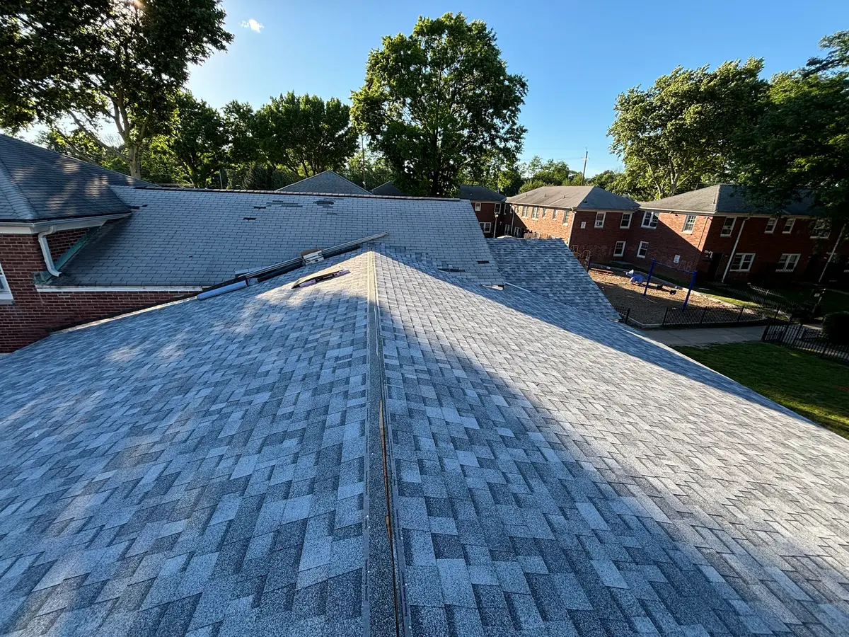 A newly shingled roof running from the ridge down to the eaves on a sunny day in Orange, New Jersey