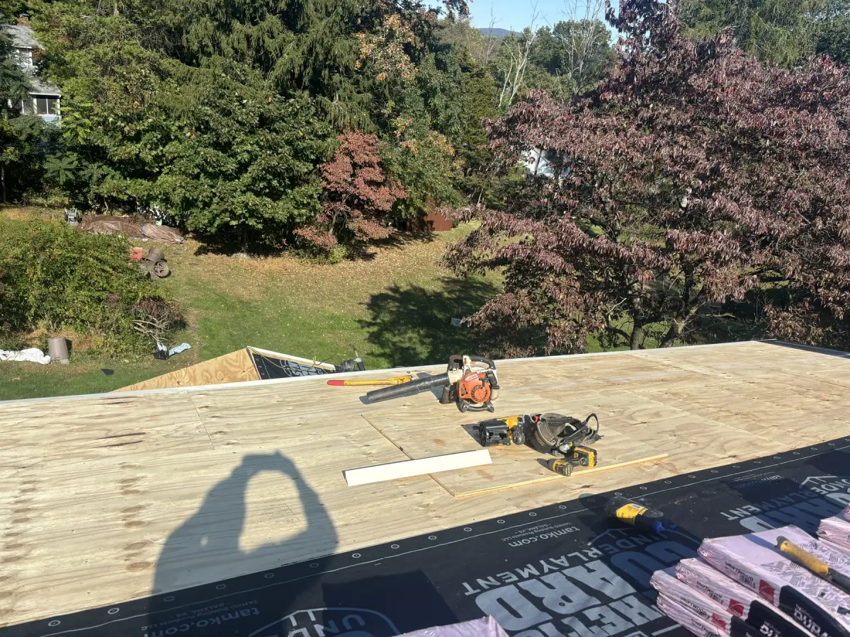 Underlayment rolled out across a new roof deck with tools resting on it