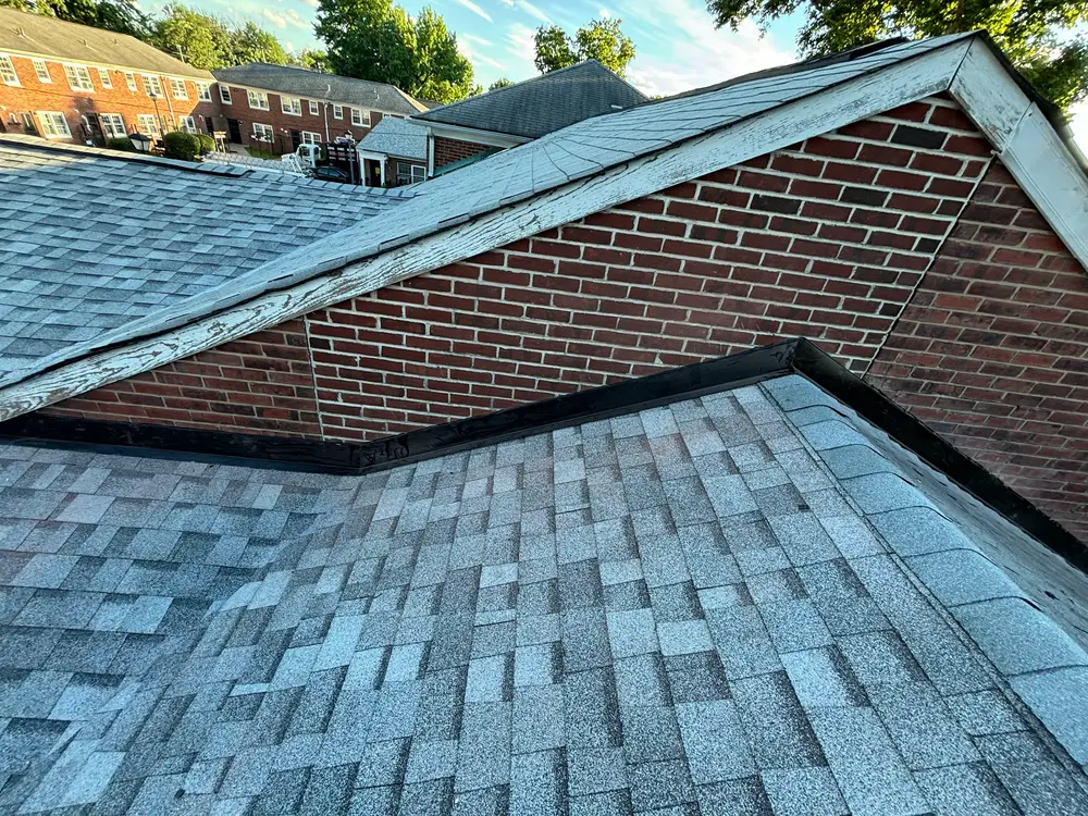 A shingle roof valley worked in tight against a brick gable wall