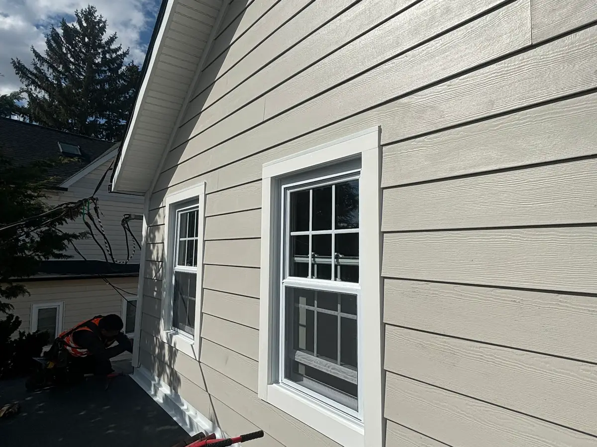 New grey lap siding and white window trim on the side of a house, photographed along the wall