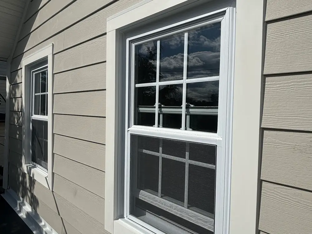 A window in white trim set into newly fitted grey siding