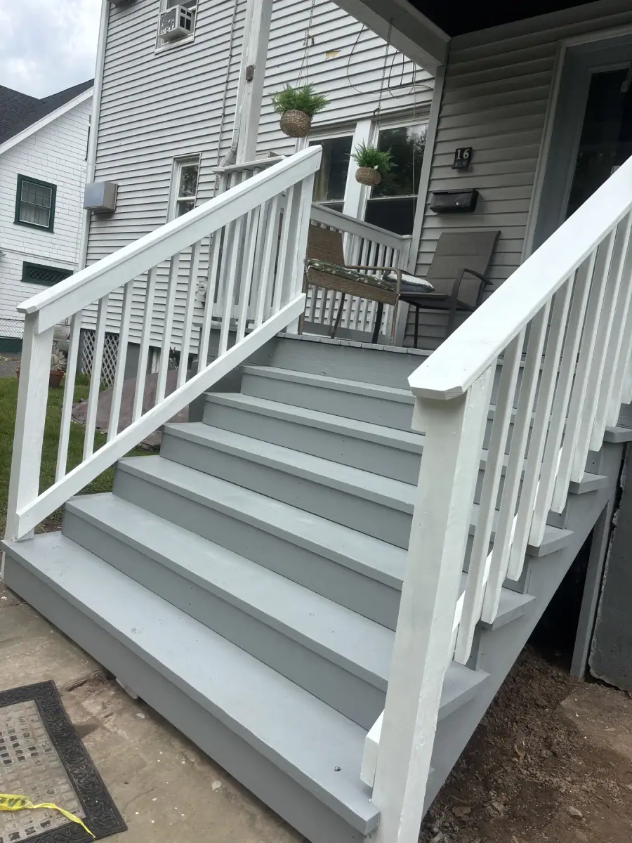 Finished steps painted grey with a white railing running down beside them